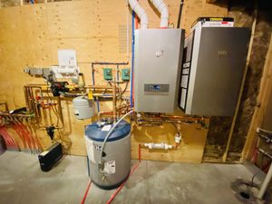 A photo of a wall mounted boiler with a wall mounted storage tank and completed piping.